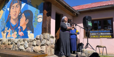Sandra Agüero, presidenta de la Casa de Artesanas, dirigiéndose a los presentes junto al Mural realizado con docentes y alumnos de la Tecnitatura Superior de Gestión Cultural del IESA 818.